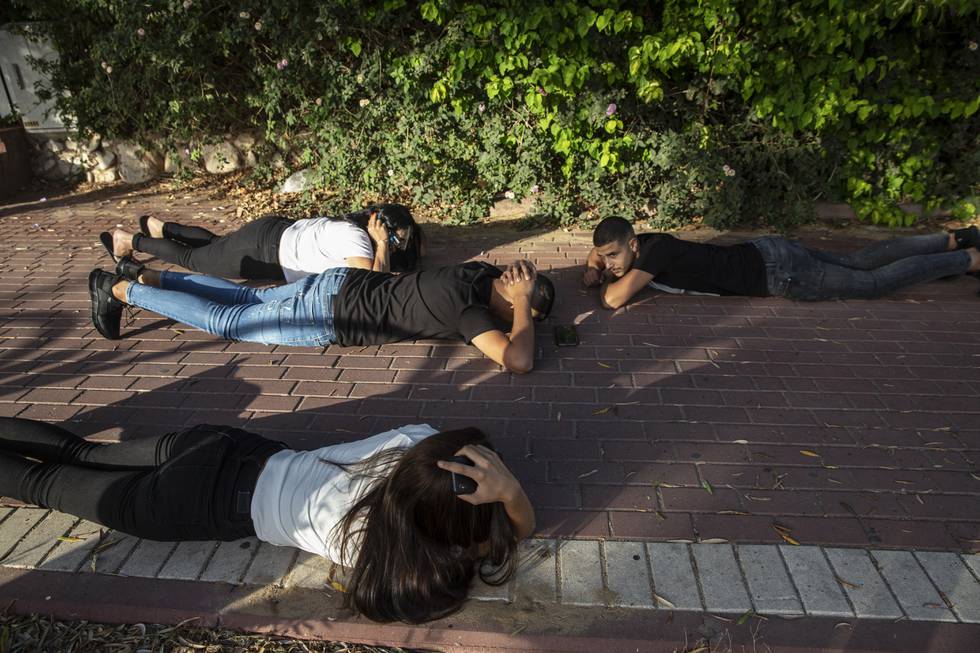 Israelere forsøker å ta dekning mens luftsirenene går i Ashkelon, nær Gazastripen. Sivilbefolkningen lider, og begge parter i konflikten anklages for krigsforbrytelser. Foto: Heidi Levine / AP / NTB