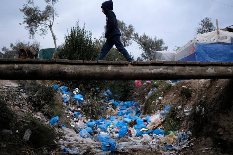 A migrant boy walks over discarded garbage outside the Moria refugee camp on the northeastern Aegean island of Lesbos, Greece, on Tuesday, Jan. 21, 2020, as some businesses and public services are holding a 24-hour strike to protest the migration situation. Thousands of migrants and refugees are stranded in massively overcrowded camps on the islands in increasingly precarious conditions. (AP Photo/Aggelos Barai)