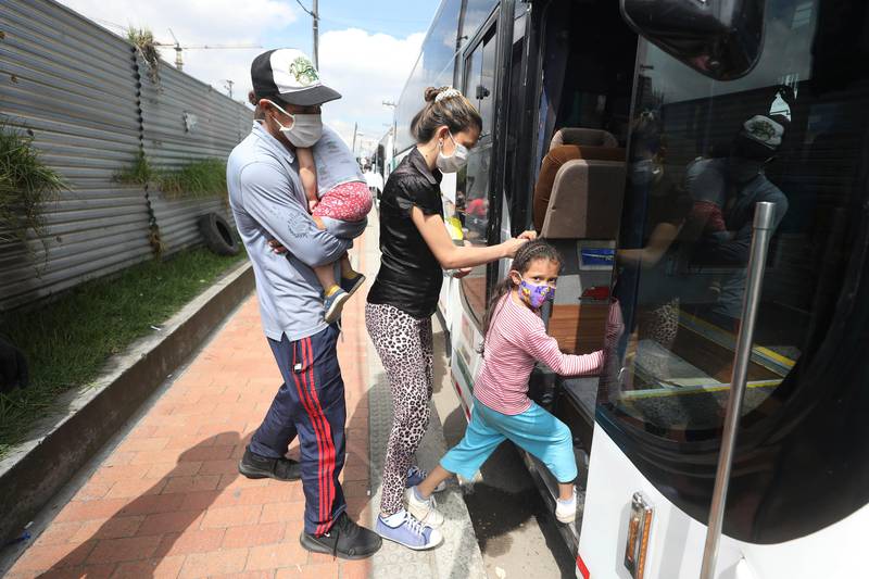 In this April 30, 2020 photo, Venezuelan migrants board a bus departing to the Venezuelan border amid the new coronavirus pandemic, in Bogota, Colombia. The Colombian government say it has paid for some of the bus trips to take the returning migrants to the Venezuelan border. (AP Photo/Fernando Vergara)