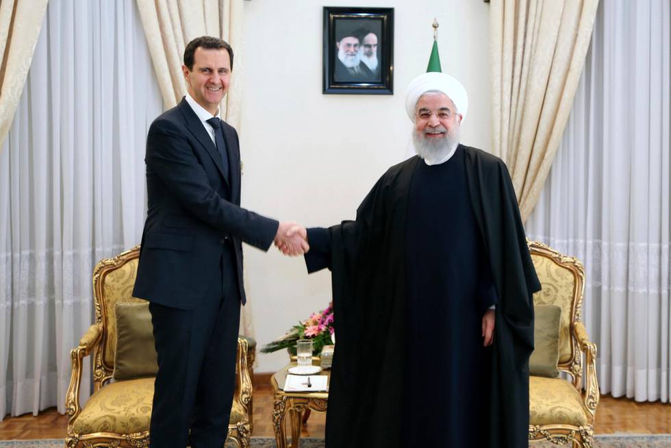 FILE - In this February 25, 2019 file photo, released by an official website of the office of the Iranian Presidency, President Hassan Rouhani, right, shakes hands with Syrian President Bashar Assad before their meeting at his office in Tehran, Iran. Assad is the last man standing among a crop of Arab dictators after the fall of the Sudanese and Algerian leaders. He's survived an 8-year war to topple him and an Islamic caliphate over part of his broken country. But Bashar Assad's path is strewn with difficulties and the war for Syria is far from over. (Office of the Iranian Supreme Leader via AP, File)