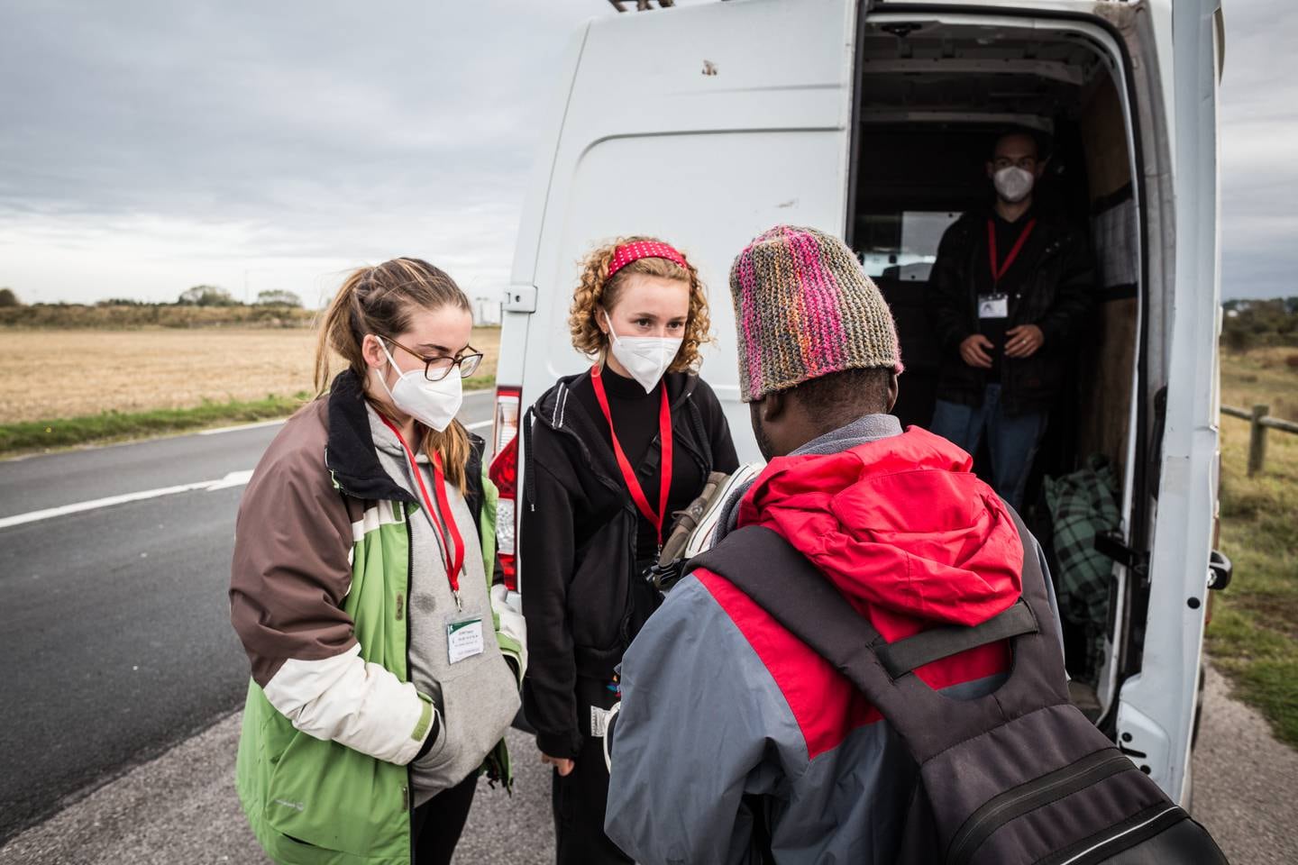 27.	Kayleigh and Liddy, to frivillige i Collective Aid, snakker med Ali, en ung sudanesisk migrant utenfor Old Lidl, den største migrantleiren i Calais.