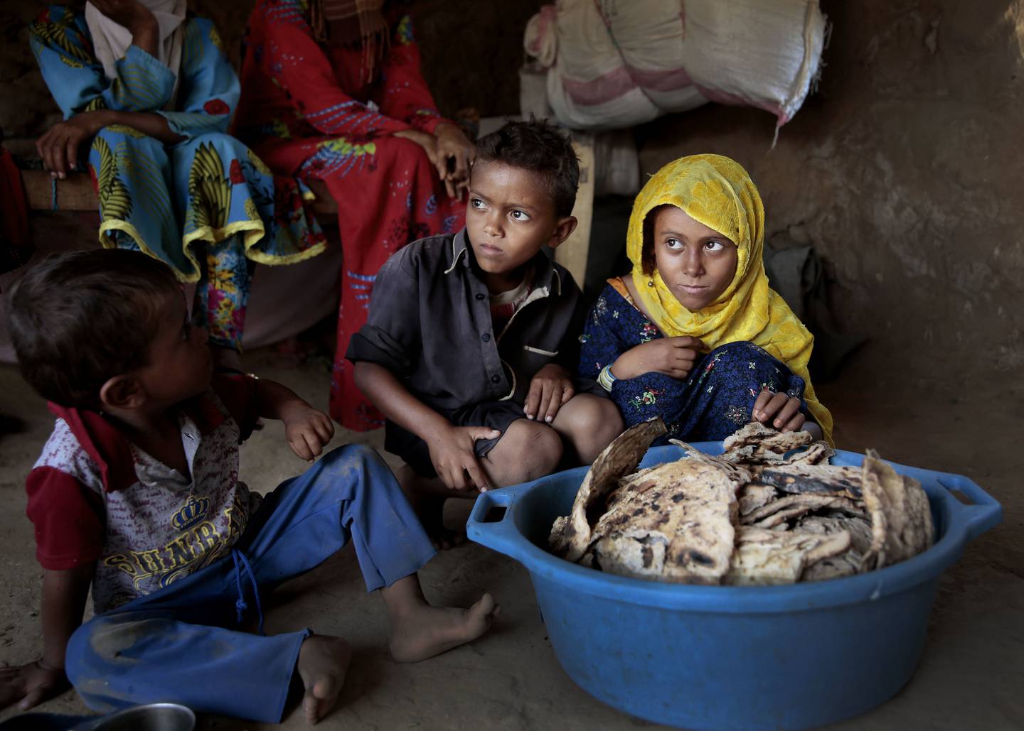 FILE - In this Oct. 1, 2018 file photo, children sit in front of moldy bread in their shelter, in Aslam, Hajjah, Yemen.