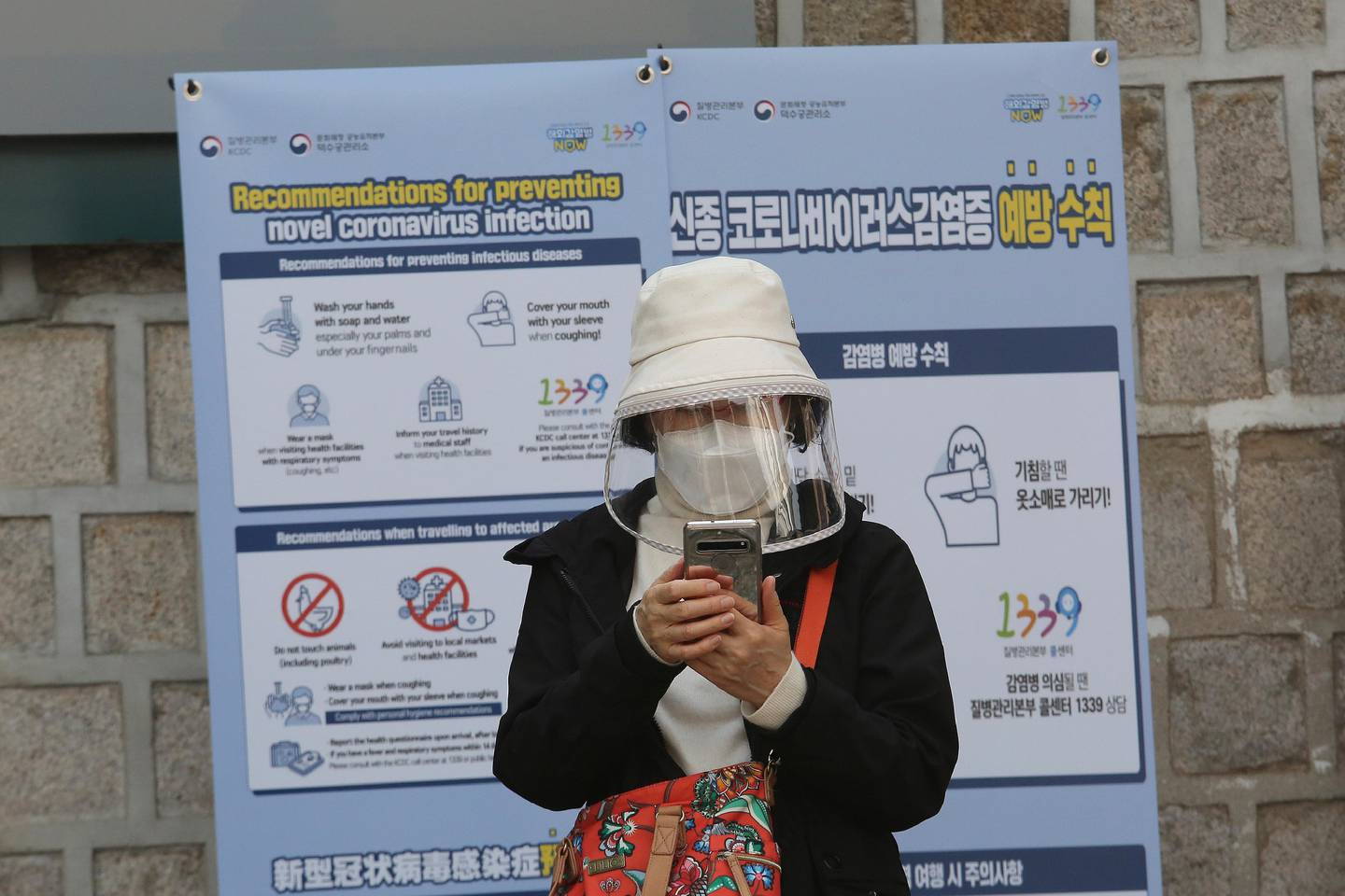 A woman wearing a face mask watches her smartphone in Seoul, South Korea, Saturday, March 21, 2020. For most people, the new coronavirus causes only mild or moderate symptoms, such as fever and cough. For some, especially older adults and people with existing health problems, it can cause more severe illness, including pneumonia. (AP Photo/Ahn Young-joon)
