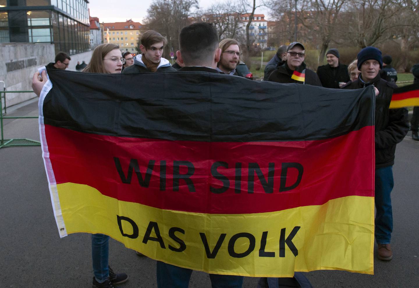 People attend a so called 'A light for democracy' silent demonstration, initiated by the far-right Alternative for Germany (AfD) party in Erfurt, central Germany, Tuesday, March 3, 2020. The words at the German flag read 'We are the people'. The parliament of the eastern German state Thuringia will elect a new governor on Wednesday, March 4, 2020. (AP Photo/Jens Meyer)