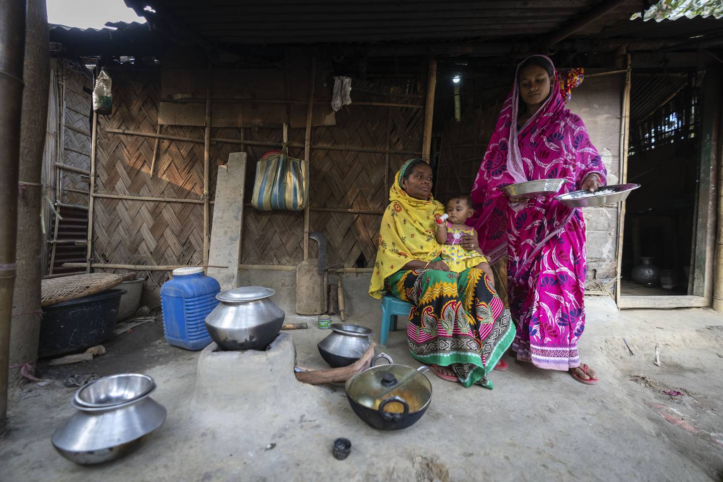 Nureja Khatun, 19, right, brings food for her mother in law in their shanty home, in Morigaon district of Indian northeastern state of Assam, Saturday, Feb. 11, 2023. Khatun's husband Akbor Ali is one among more than 3,000 men, including Hindu and Muslim priests, who were arrested nearly two weeks ago in the northeastern state of Assam under a wide crackdown on illegal child marriages involving girls under the age of 18. (AP Photo/Anupam Nath)
