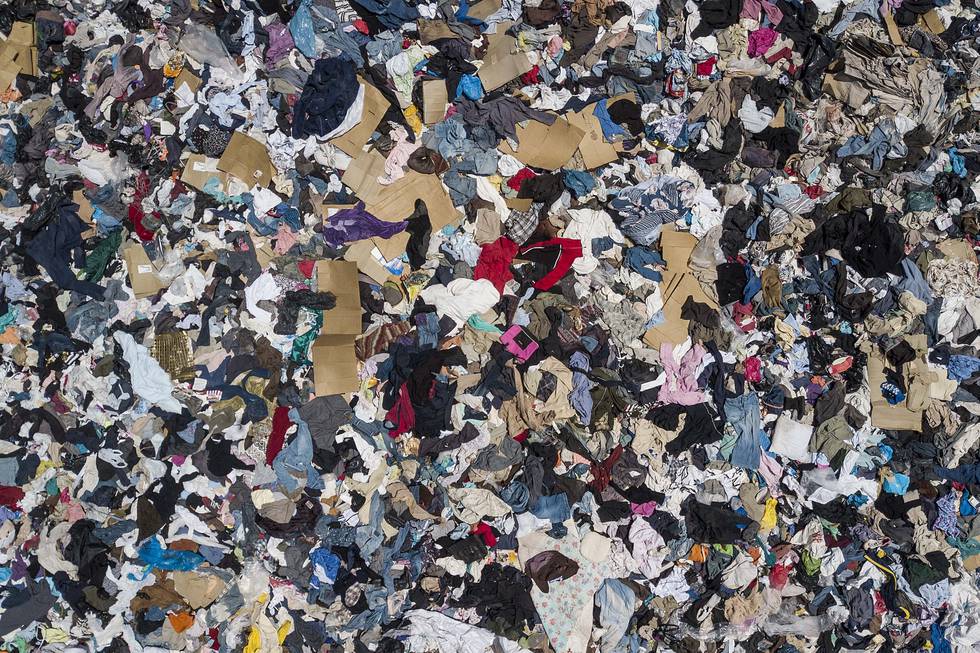 A large pile of second-hand clothing covers the sand near La Mula neighborhood in Alto Hospicio, Chile, Monday, Dec. 13, 2021. Chile is a big importer of second hand clothing, and unsold clothing gets dumped here. (AP Photo/Matias Delacroix)