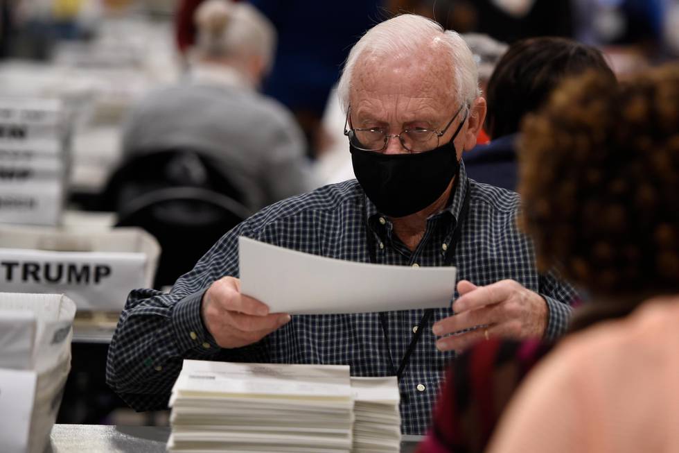 Cobb County Election officials handle ballots during an audit, Monday, Nov. 16, 2020, in Marietta, Ga. A hand tally of the nearly 5 million votes cast in the presidential race in Georgia has entered its fourth day Monday. (AP Photo/Mike Stewart)