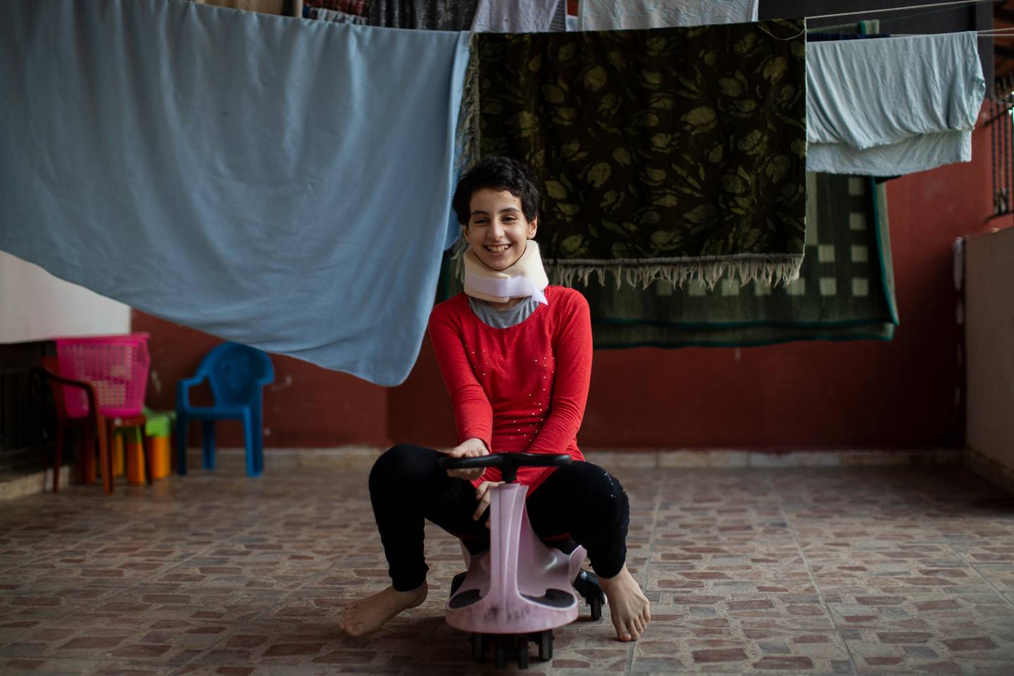 Hoda Kinno, 11, smiles as she plays in a temporary apartment in the coastal town of Jiyeh, south of Beirut, Lebanon, Tuesday, Sept. 22, 2020. The Kinno family from Syria's Aleppo region was devastated in the wake of the Aug. 4 explosion at the Beirut port -- Hoda suffered a broken neck and other injuries and her sister Sedra, 15, died in the explosion. (AP Photo/Hassan Ammar)