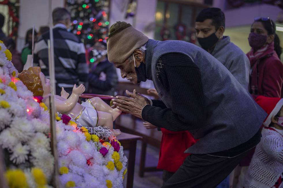 An elderly Indian Christian man touches the feet of the statue of baby Jesus after attending a Christmas mass at Saint Mary's church in Noida, a suburb of New Delhi, India, Saturday, Dec. 25, 2021. (AP Photo/Altaf Qadri)
