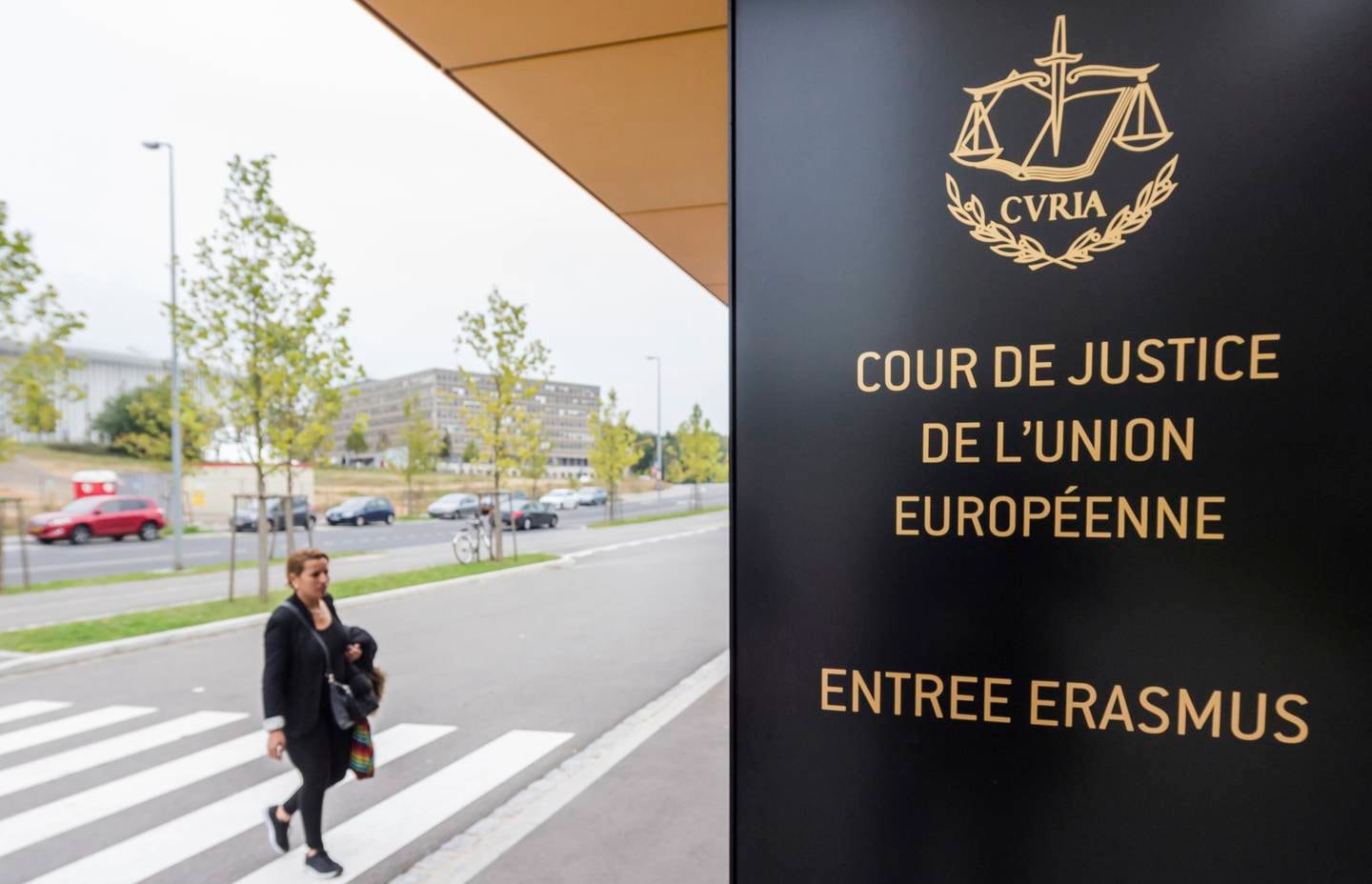 In this photo taken on Monday, Oct. 5, 2015 a woman walks by the entrance to the European Court of Justice in Luxembourg. The European Union's top court ruled Monday, Dec. 10, 2018, that Britain can change its mind over Brexit, boosting the hopes of people who want to stay in the EU that the process can be reversed. (AP Photo/Geert Vanden Wijngaert)