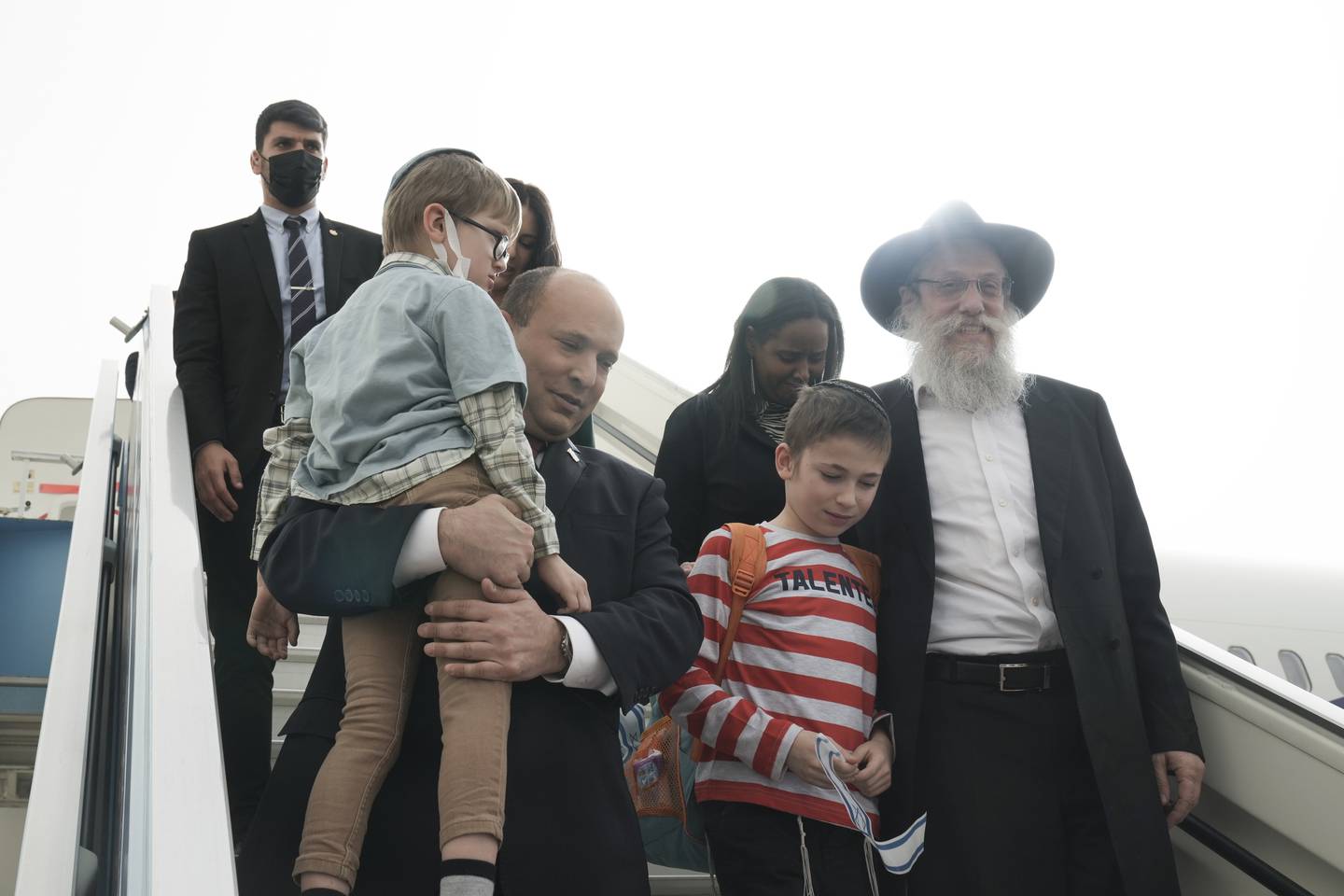 ADDA RABBI'S NAME - Israeli Prime Minister Naftali Bennett welcomes a group of orphans from the Alumim orphanage in the Ukrainian city of Zhytomyr, on arrival to Israel at Ben Gurion Airport, Sunday, March 6, 2022. To Bennett’s right is Chabad Rabbi Shlomo Wilhelm, of Zhytomyr, Ukraine.(AP Photo/Maya Alleruzzo, Pool)