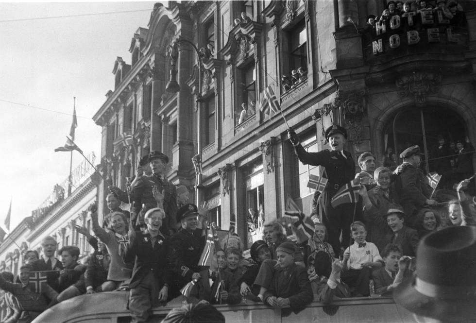 Oslo 19450508:  Fredsdagene mai 1945. Frigjøringsdagen 8. mai, jubel på Karl Johans gate. Biler fulle av jublende mennesker med norske flagg, folkemengder i gatene.
Foto: Kihle / NTB / Scanpix
