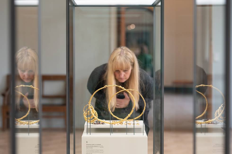 Portrett av Cat Jarman ved Vikingutstilling på Kulturhistorsik Museum i Oslo. Her tar hun bilder av hennes favoritt del av utstilling. De store  gull ringene ble funnet av en bonde som plutselig fikk de på spade han jobbet med.