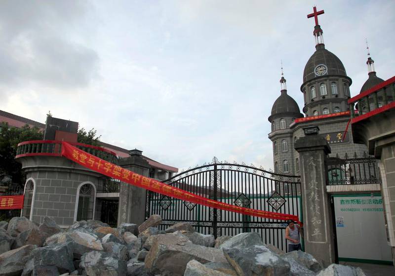 I byen Zengshan Village har kristne stablet store steinar foran porten til kirken for å hindre myndigheter og politi å rive ned korset på kirken. Det røde båndet viser at de påberoper seg å bli beskyttet av loven om religiøs frihet. 