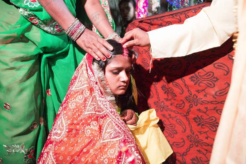 Med tommelen tegner Ashok en stripe med lysende rød sindoor – et kosmetisk pulver – langs skillet i håret til sin unge ektefelle Punam. Den hinduistiske skikken markerer at hun er en gift kvinne.