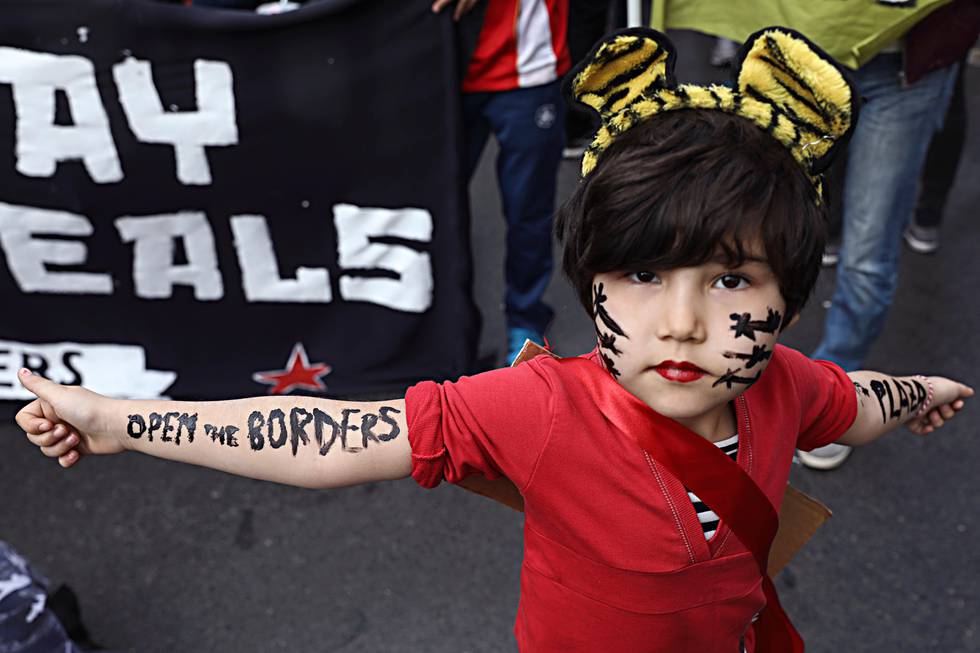 A girl poses for a photo during a rally against the EU-Turkey deal blocking mass migration into Europe , in Athens, Saturday, March 17, 2018. About 2,000 protesters marched to the EU offices chanting against closed borders, but also against Turkish president Recep Tayyip Erdogan and Turkey's incursion into Syria, on a day when a boat that sank off a Greek island while smuggling migrants or refugees left at least 16 people dead. (AP Photo/Yorgos Karahalis)