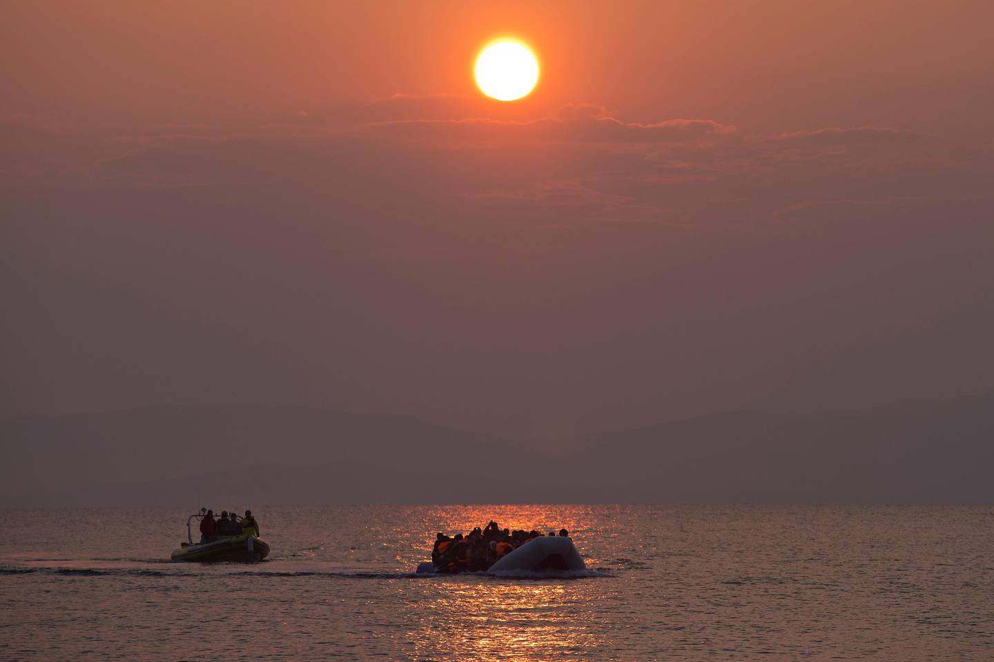 The sun rises as migrants and refugees on a dingy arrive at the shore of the northeastern Greek island of Lesbos, after crossing the Aegean sea from Turkey on Sunday, March 20, 2016. In another incident two Syrian refugees have been found dead on a boat on the first day of the implementation of an agreement between the EU and Turkey on handling the new arrivals. (AP Photo/Petros Giannakouris)