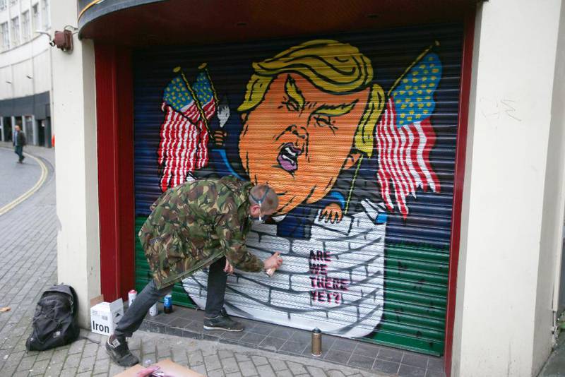 En britisk gatekunstner i Bristol framstiller Trump som en  amerikansk isolasjonist bak høye murer. Nå mykner Trump opp flere av sine hardeste standpunker.
