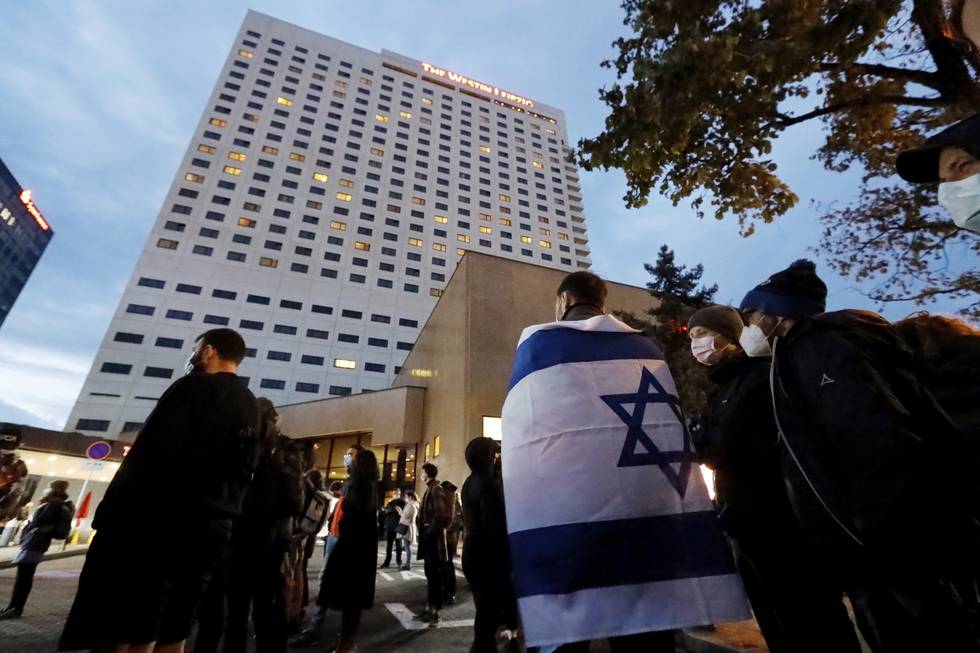 People gather in front of the "Westin Hotel" in Leipzig, Germany, Tuesday, Oct. 5, 2021 to show solidarity with the musician Gil Ofarim. A leading Jewish group in Germany says it's shocked by a German-Israeli singers report of being turned away from a hotel because he was wearing a Star of David pendant. Singer Gil Ofarim, who lives in Germany, shared a video on Instagram Tuesday showing him in front of the Westin hotel in Leipzig and saying a hotel employee asked him to put away his necklace in order to check in. (Dirk Knofe/dpa via AP)