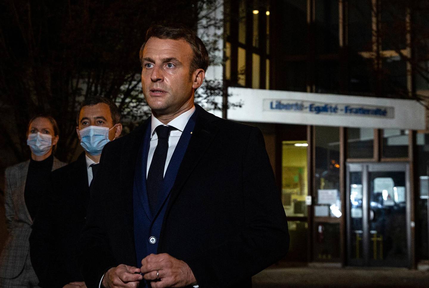 French President Emmanuel Macron, flanked by French Interior Minister Gerald Darmanin, second left, speaks in front of a high school Friday Oct.16, 2020 in Conflans Sainte-Honorine, northwest of Paris, after a history teacher who opened a discussion with high school students on caricatures of Islam's Prophet Muhammad was beheaded. French President Emmanuel Macron denounced what he called an "Islamist terrorist attack" against a history teacher decapitated in a Paris suburb Friday, urging the nation to stand united against extremism. (Abdulmonam Eassa, Pool via AP)