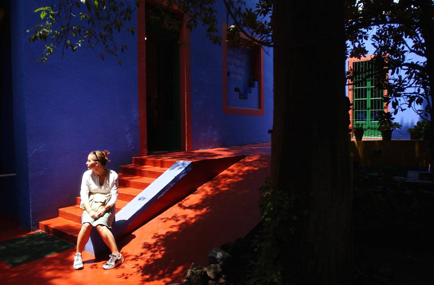 A visitor sits in the courtyard of artist Frida Kahlo's Blue House Thursday July 8, 2004, in Mexico City. Frida Kahlo was born and lived there until 1954. The house has been repainted to reflect its appearance during Kahlo's years of residence. Fifty years after  Kahlo's death her very private, raw and vulnerable work is only getting more popular.(AP Photo/Jose Luis Magana)