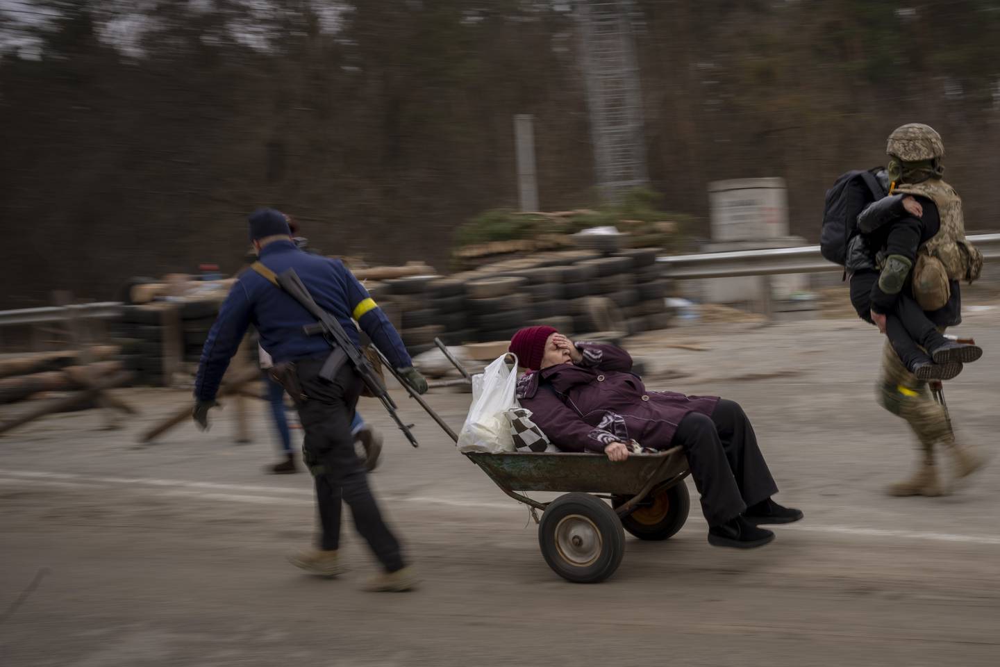 HJELP: En ukrainsk soldat og militsmann hjelper en kvinne over elven Irpin. Kvinner er utsatte for voldtekt i krig.