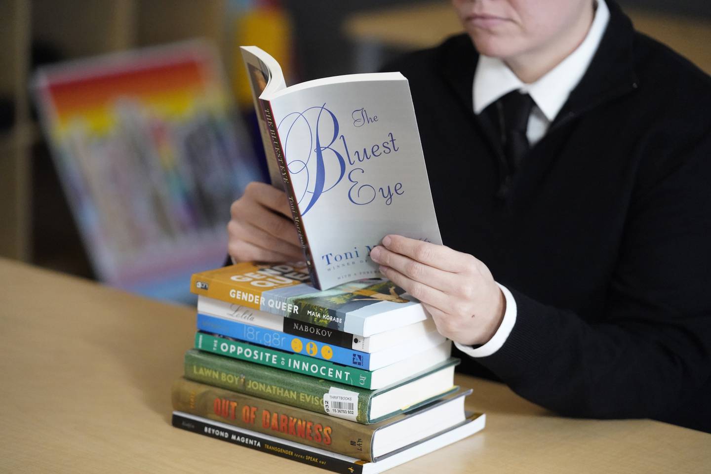 FILE - Amanda Darrow, director of youth, family and education programs at the Utah Pride Center, poses with books, including "The Bluest Eye," by Toni Morrison, that have been the subject of complaints from parents in Salt Lake City on Dec. 16, 2021. The wave of book bannings around the country has reached a level not seen for decades. (AP Photo/Rick Bowmer, File)