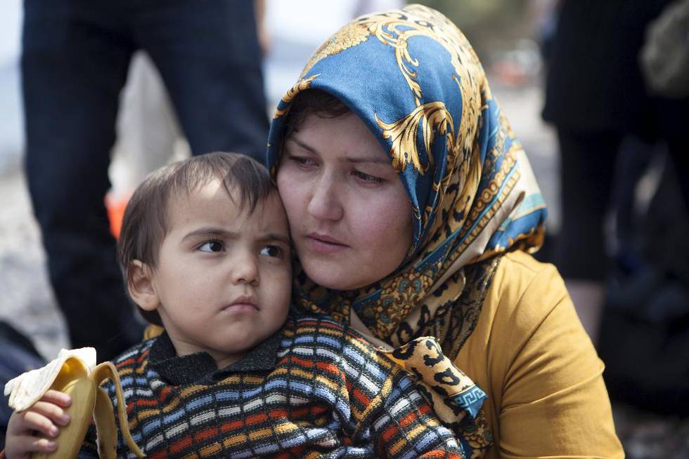 En afghansk kvinne holder et barn etter at de har kommet seg over havet til øya Lesbos i Hellas. Ifølge innvandringminister i landet, Yannis Mouzalas, er det mellom 15.000 og 18.000 migranter på øya nå.