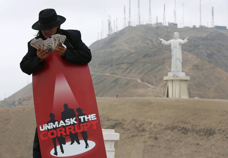 A man counts play money backdropped by the statue, Cristo del Pacifico or "the Christ of the Pacific" during a demonstration against corruption, in Lima, Peru, Thursday, Nov. 12, 2015. Peruvians joined the global campaign, "Unmask The Corrupt",  launched by the non-governmental organization Transparency International, that calls for world leaders to stop corrupt politicians and business people from escaping justice. (AP Photo/Martin Mejia)