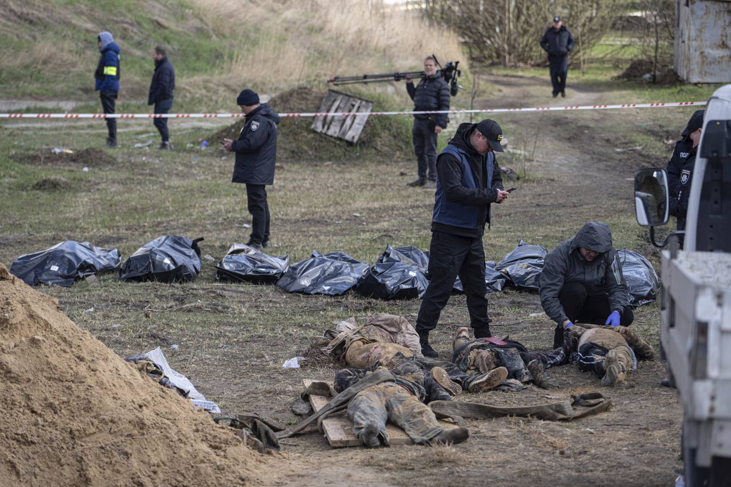 Ukrainske rettsmedisinere og politi deltar i dokumentasjonen av hvordan lokale innbyggere er blitt drept i forstedene til Kyiv. Her fotograferes lik som er hentet ut av en massegrav i Butsja. Mange av ofrene er menn i 50- og 60-årsalderen, ifølge ukrainske kilder. Flere av dem skal ha blitt torturert. Foto: Jevgenij Maloletka / AP / NTB