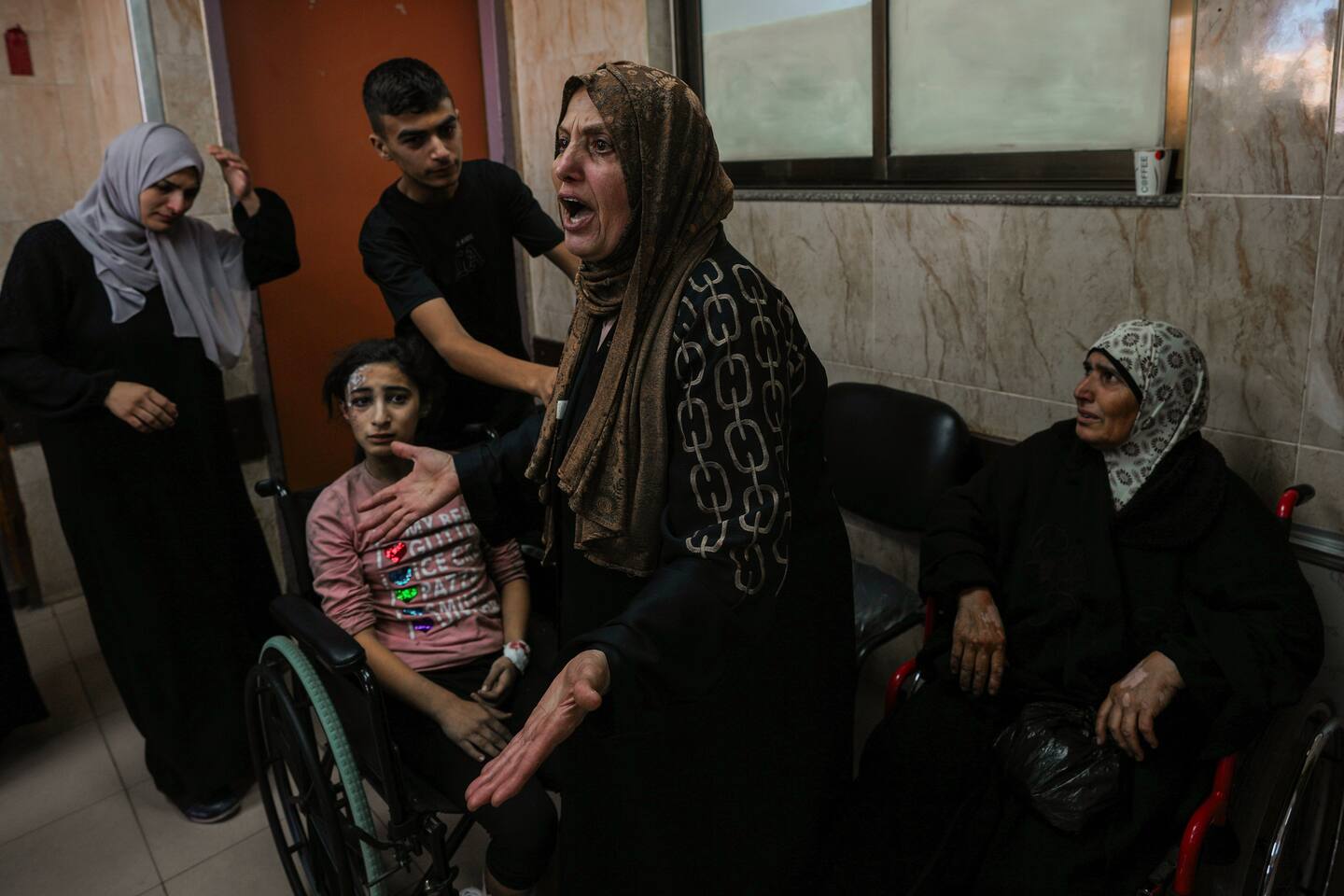 At al-Aqsa hospital in Deir el-Balah, central Gaza Strip, a Palestinian woman reacts next to the wounded during an Israeli airstrike, Sunday, Oct. 15, 2023. (AP Photo/Adel Hana)