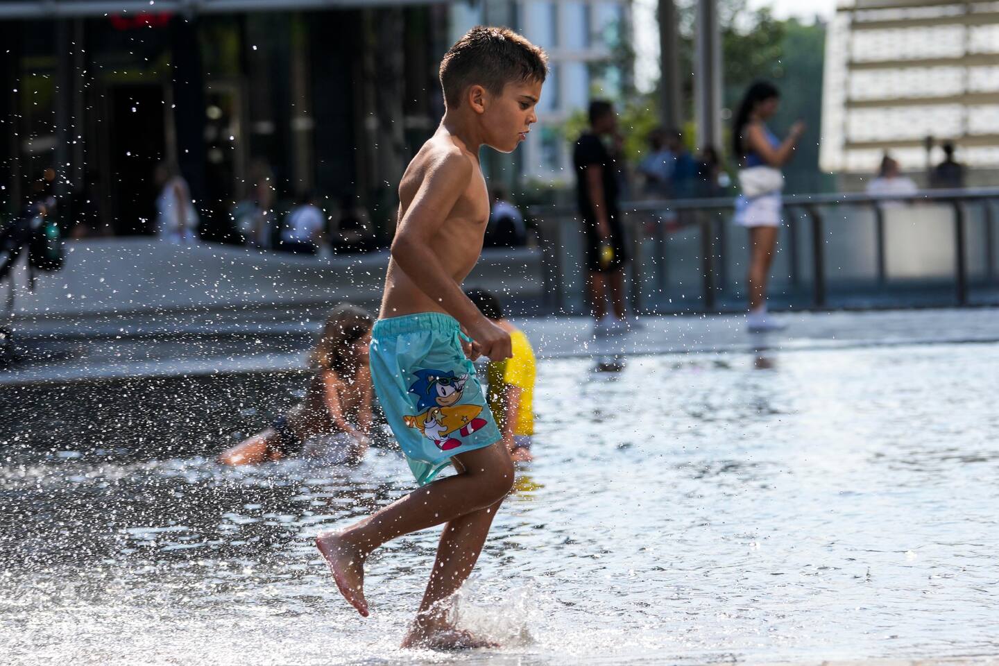 Barn kjøler seg ned i en fontene i Milano i Italia, der temperaturen denne uka nådde opp i 42 grader noen steder. Foto: Luca Bruno / AP / NTB