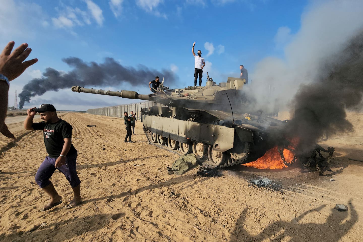 Palestinere feirer ved en ødelagt israelsk stridsvogn på Gazastripen, ved grensegjerdet øst for Khan Younis lørdag. Foto: Hassan Eslaiah / AP / NTB