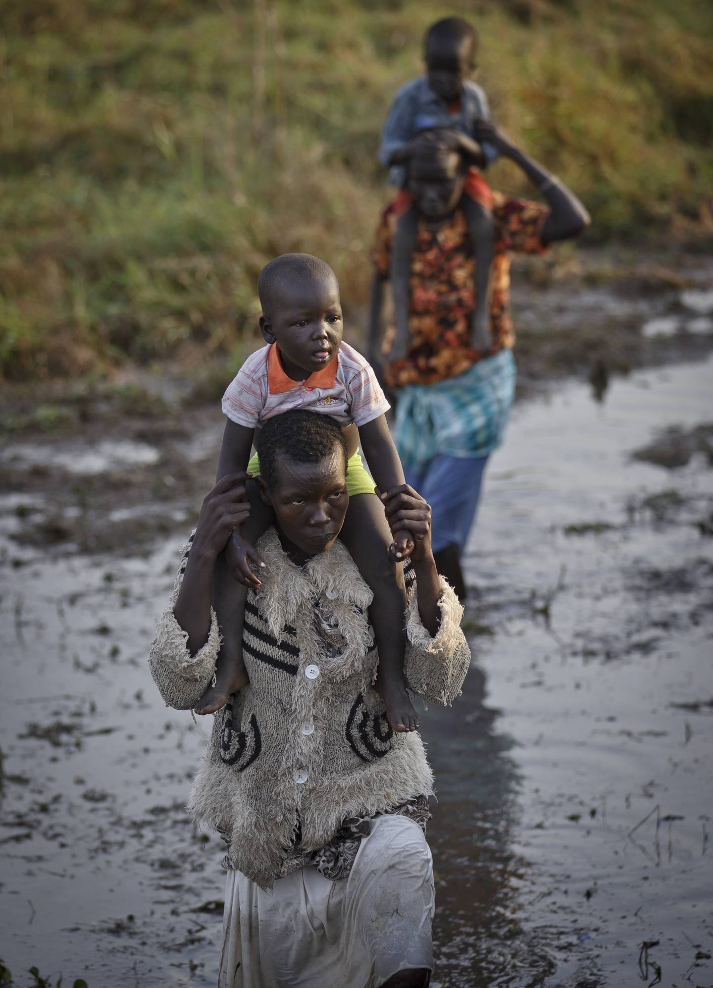 Displaced people wade through mud as they get off a river barge from Bor, some of the thousands who fled the recent fighting between government and rebel forces in Bor by boat across the White Nile, in the town of Awerial, South Sudan Thursday, Jan. 2, 2014.