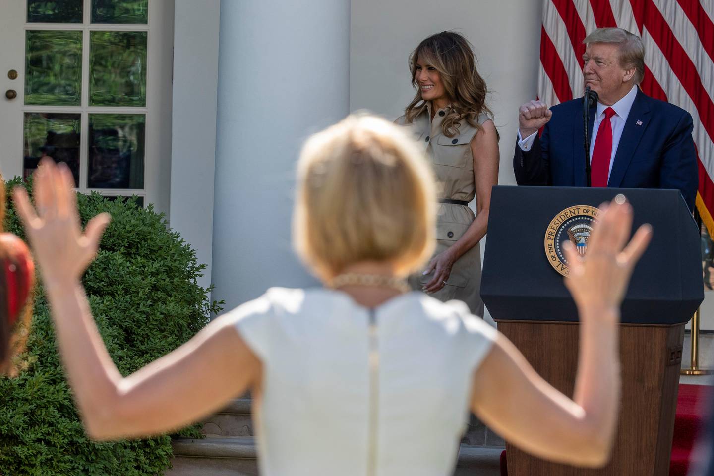 President Donald Trump stands with first lady Melania Trump as White House spiritual adviser Paula White, left foreground, raises her hands in praise during a White House National Day of Prayer Service in the Rose Garden of the White House, Thursday, May 7, 2020, in Washington. (AP Photo/Alex Brandon)
