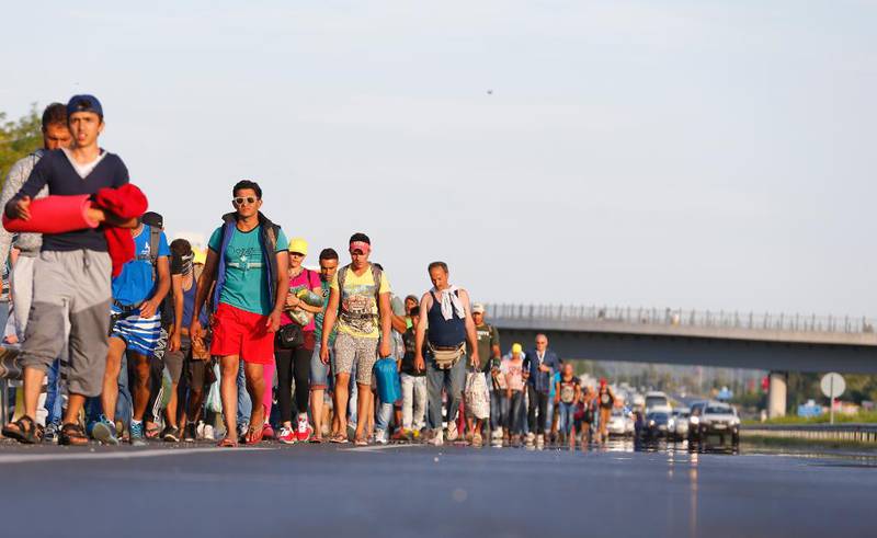 Migranter går langs hovedveien mot Østerrikes grense, ut av Budapest. Hundrevis av flyktninger brøt ut av en flyktningleir i Ungarn og begynte fredag å gå mot Østerrike til fots. Foto: REUTERS/Laszlo Balogh  