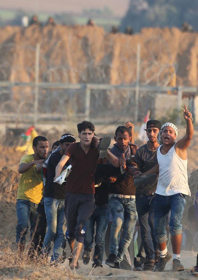 En skadet palestinsk demonstrant hjelpes bort etter å ha blitt skutt av israleske styrker under et sammenstøt nær grensen til den sentrale Gaza-stripen 17. oktober.