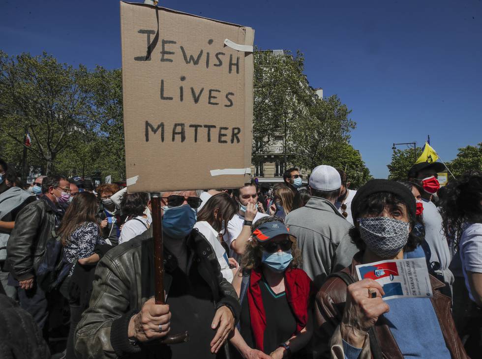 A man holds a placard during a protest organized by Jewish associations, who say justice has not been done for the killing of French Jewish woman Sarah Halimi, at Trocadero Plaza near Eiffel Tower in Paris, Sunday, April 25, 2021. Thousands of people have gathered in Paris and other French cities to denounce a ruling by France's highest court that the killer of Jewish woman Sarah Halimi was not criminally responsible and therefore could not go on trial. (AP Photo/Michel Euler)