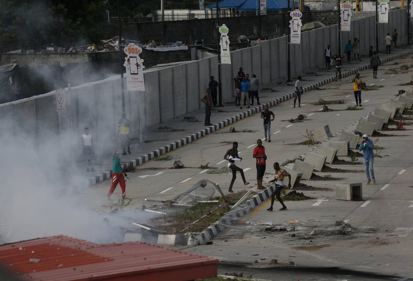 Protesters run away as police officers use teargas to disperse people demonstrating against police brutality in Lagos, Nigeria, Wednesday Oct. 21, 2020. After 13 days of protests against alleged police brutality, authorities have imposed a 24-hour curfew in Lagos, Nigeria's largest city, as moves are made to stop growing violence. ( AP Photo/Sunday Alamba)