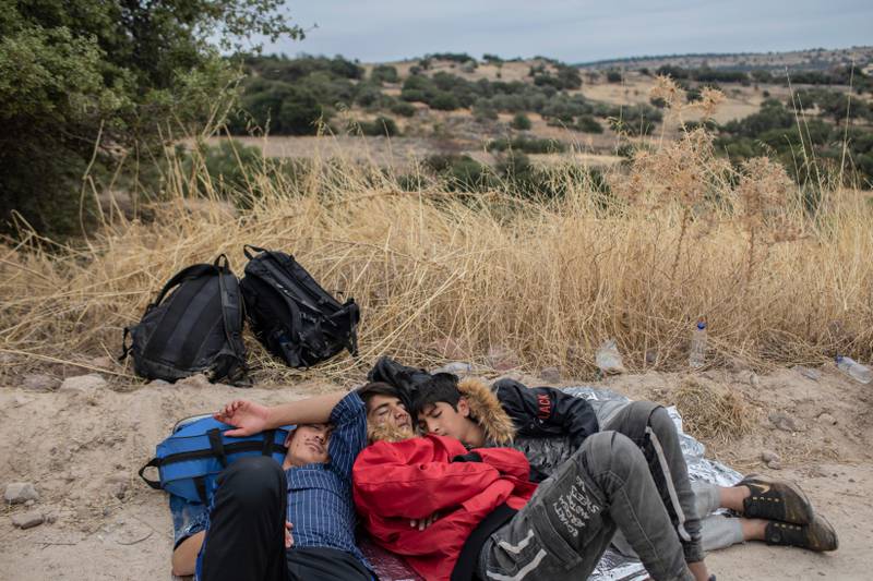 In this Monday, Oct. 7, 2019 photo, exhausted Afghan youths sleep on the ground near the town of Madamados after their arrival with other migrants and refugees on a rubber boat from Turkey, at Lesbos Island, Greece. (AP Photo/Petros Giannakouris)