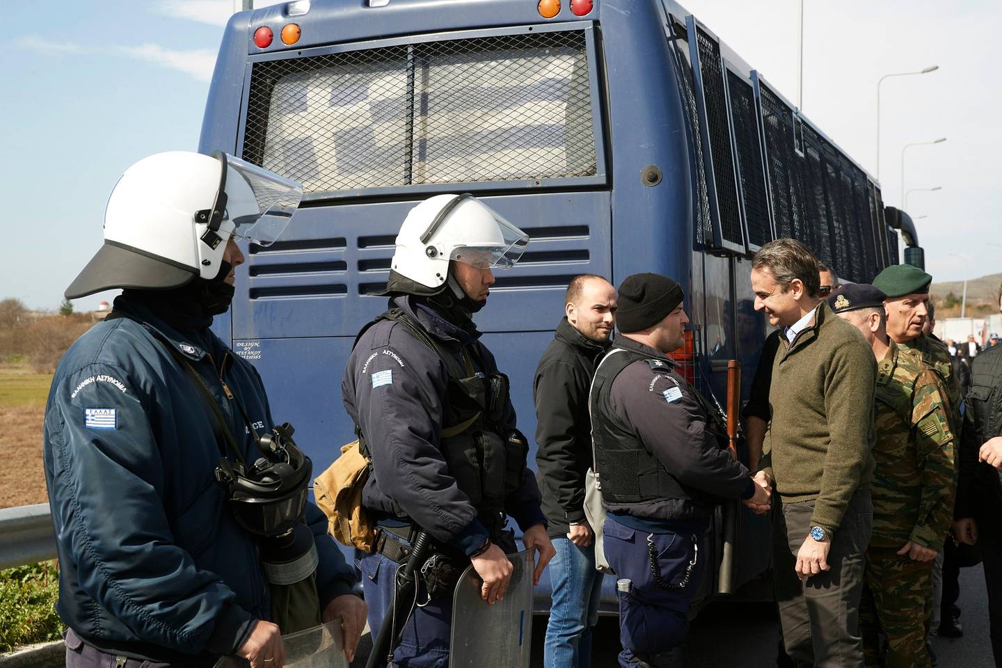 Greece's Prime Minister Kyriakos Mitsotakis, right, shakes hands with a police officer near the Kipoi border gate, Evros region, at the Greek-Turkish border on Tuesday, March 3, 2020. Migrants and refugees hoping to enter Greece from Turkey appeared to be fanning out across a broader swathe of the roughly 200-kilometer-long land border Tuesday, maintaining pressure on the frontier after Ankara declared its borders with the European Union open. (Dimitris Papamitsos/Greek Prime Minister's Office via AP)