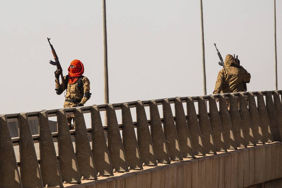 Soldater som hevdes å forsøke seg på militærkupp, står på en bro ved en militærleir i Burkina Fasos hovedstad. Vitner har meldt om kraftig skuddveksling på basen og i nærheten av presidentpalasset søndag. Foto: P Photo / Sophie Garcia / NTB