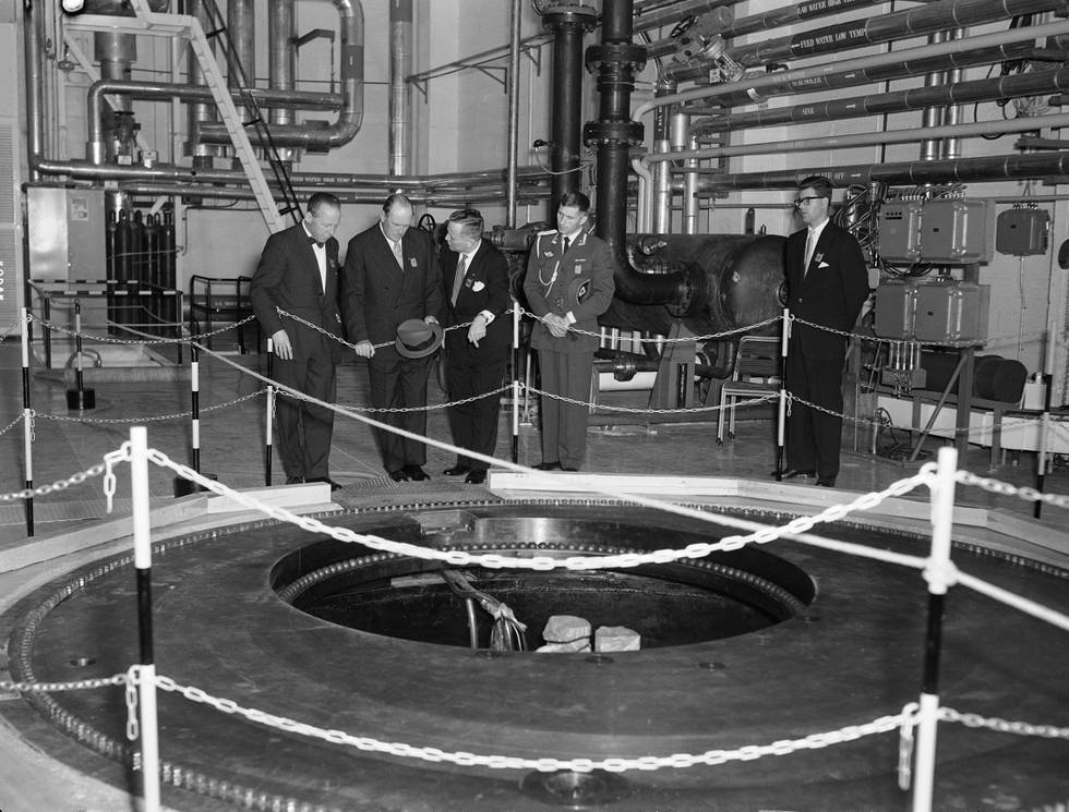 HALDEN 10101959 Atomreaktoren i Halden, åpningsseremonien, Kong Olav tilstede.  Reaktoren i Halden ble bygget i perioden 1955 til 1958 av daværende Institutt for Atomenergi (nå Institutt for Energiteknikk, IFE). Reaktoren ble bygget som en forsøksreaktor, med tilstrekkelig effekt til også å brukes som en prototype dampprodusent for industrien. Kjøling av reaktoren og moderering av nøytroner skjer med 14 tonn tungtvann. Denne typen reaktorer kalles en kokvannsreaktor. 
Her Kong Olav på omvisning i anlegget etter åpningen. Fra v: Direktør Gunnar Randers, Kong Olav, direktør Odd Dahl, Major Arne Haugli og direksjonssekretær Bjarne Aabakken.
Foto: Nordby NTB / Scanpix