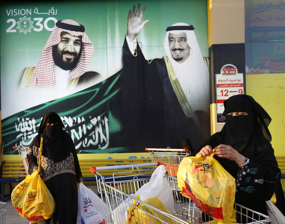 In this Wednesday, Feb. 5, 2020, photo, women carry their shopping bags past a banner showing Saudi King Salman and his Crown Prince Mohammed bin Salman, left, outside a mall in Jiddah, Saudi Arabia. Human rights organization Amnesty International says Saudi Arabia has used a special anti-terrorism court as "a weapon of repression" to imprison peaceful critics, dissidents, activists, journalists, clerics and members of the kingdom's minority Muslim Shiites, including some who were sentenced to death and executed. (AP Photo/Amr Nabil)