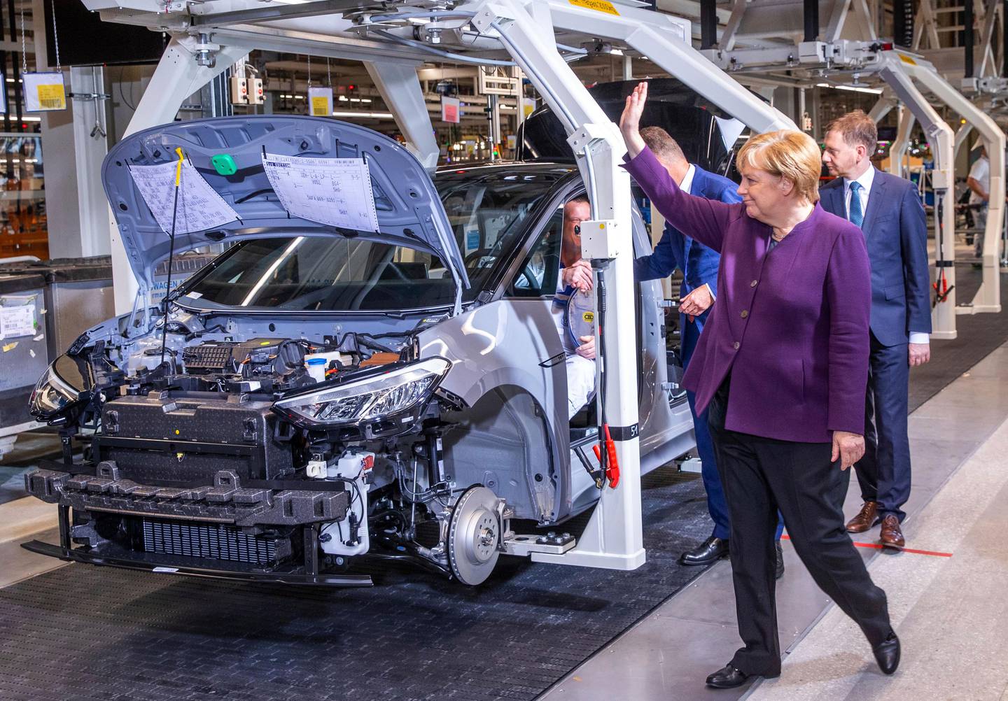 German Chancellor Angela Merkel waves to workers on the pro duction line for the production of the electric car ID.3 in Zwickau, eastern Germany, Monday, Nov.4, 2019.The vehicle is part of the new ID series with which Volkswagen is investing billions in e-mobility. (Jens Buettner/dpa via AP)