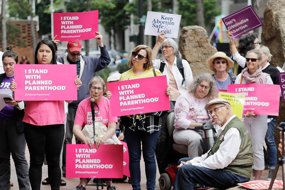 FILE - In this July 10, 2018 file photo, protesters hold signs supporting Planned Parenthood in Seattle, as they demonstrate against President Donald Trump and his choice of federal appeals Judge Brett Kavanaugh as his second nominee to the Supreme Court. On Tuesday, March 5, 2019, the American Medical Association and Planned Parenthood jointly filed a federal court lawsuit challenging a new Trump administration rule for family-planning grants which had been sought by anti-abortion activists. (AP Photo/Ted S. Warren, File)