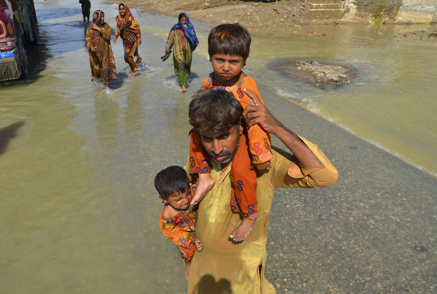 En mann bærer døtrene sine gjennom flomrammede gater i Jaffarabad i Balutsjistan-provinsen. Hjemmet deres er totalt ødelagt som følge av de voldsomme vannmengdene, og de har ikke lenger et sted å bo. Foto: Zahid Hussain / AP / NTB