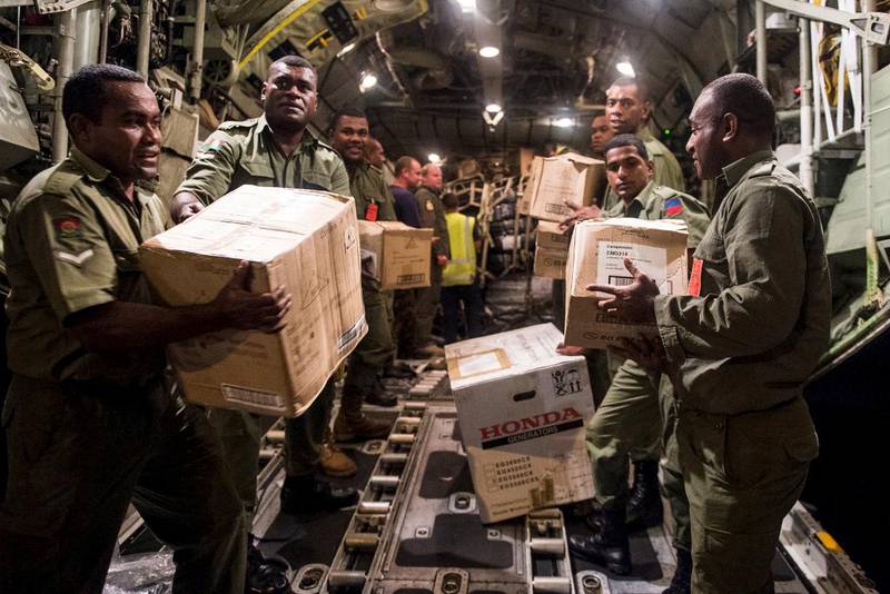 Soldater fra New Zeland sin nasjonalgarde laster av store mengder med mat og annen humanitær nødhjelp fra et militært fly. Det er blant annet slike transportutgifter som nå vil kunne kategoriseres som bistand.